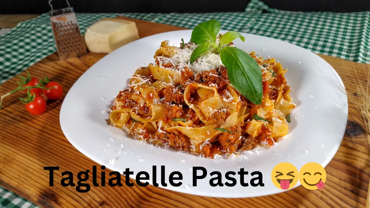 A bowl of tagliatelle pasta, featuring long, flat strands, garnished with herbs and a drizzle of olive oil.