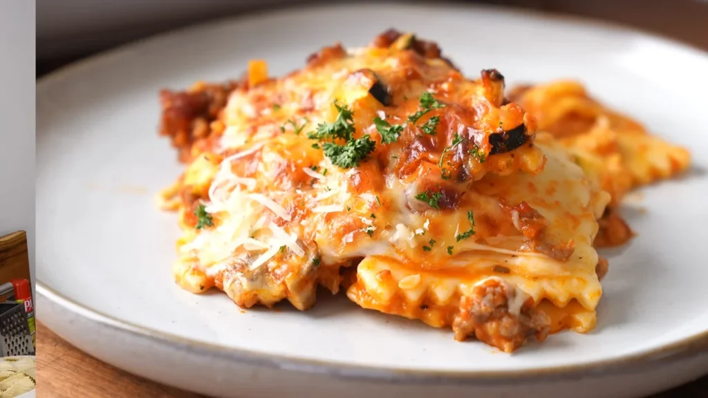 A vibrant dish of backed ravioli lasagna, featuring golden pasta layers, marinara sauce, and a sprinkle of fresh herbs.