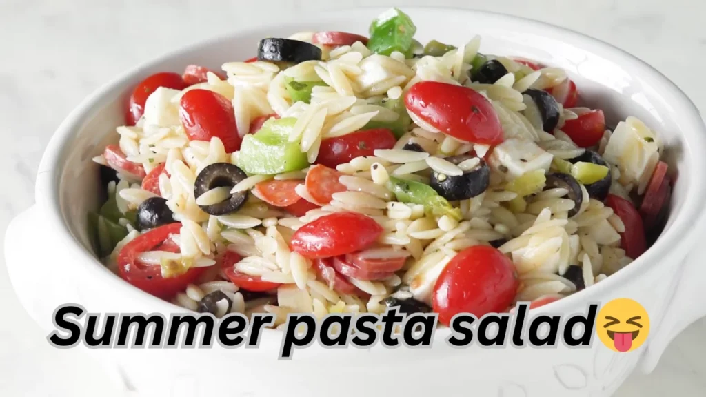 A delicious bowl of Summer pasta salad filled with juicy tomatoes, savory olives, and hearty black beans.