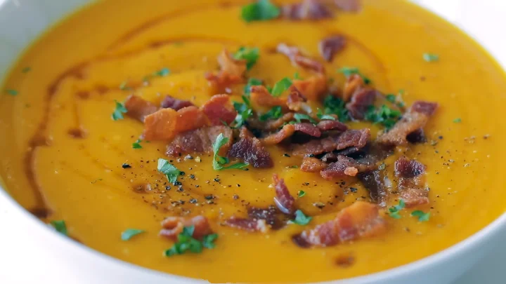 Roasted Butternut Squash Soup 2 Creamy roasted butternut squash soup garnished with a sprinkle of herbs and a drizzle of olive oil in a rustic bowl.