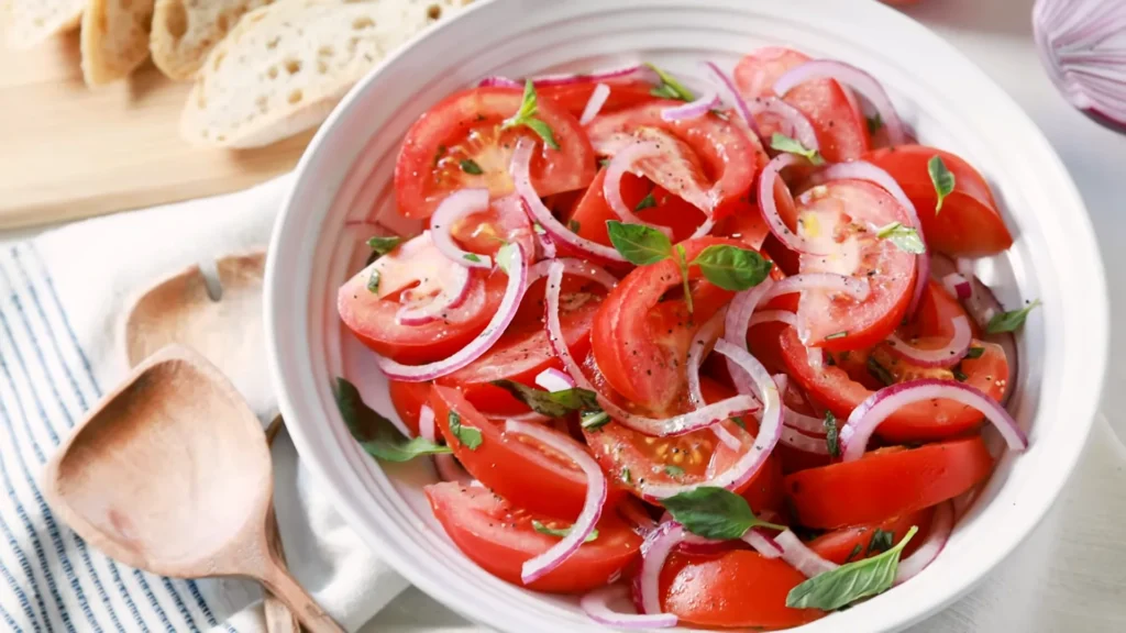 Tomato salad 2 A fresh tomato salad in a bowl, showcasing juicy tomatoes, white onions, and red onions for added flavor.